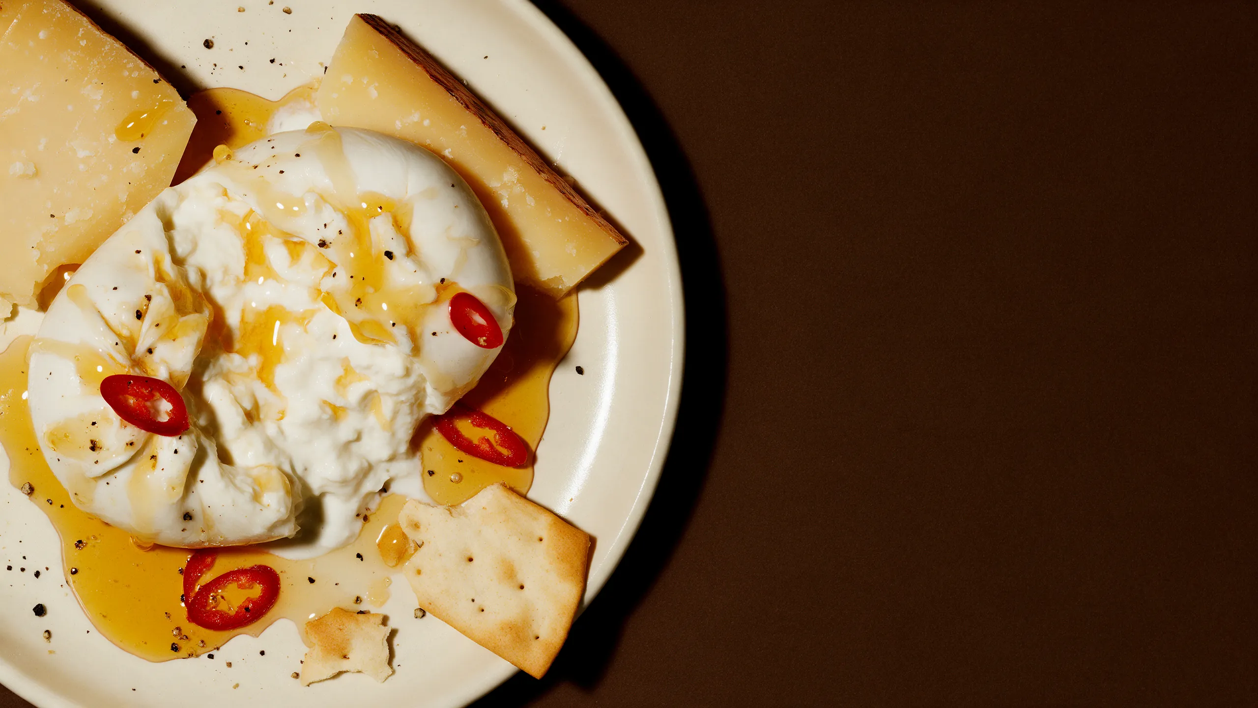Burrata ouverte et fromage affiné avec miel pimenté, rondelles de piment et crackers